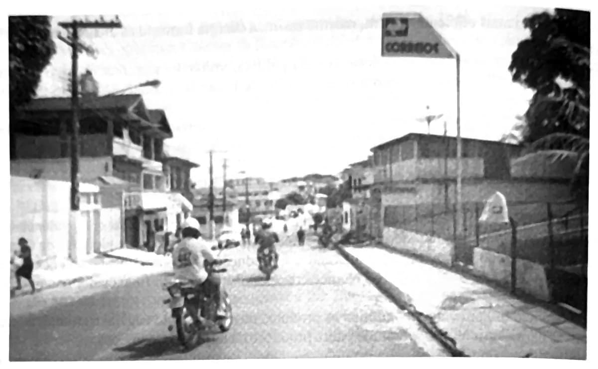Fotografia da rua Olavo Bilac em 2003, com prédios de dois pavimentos, calçada e rua pavimentada