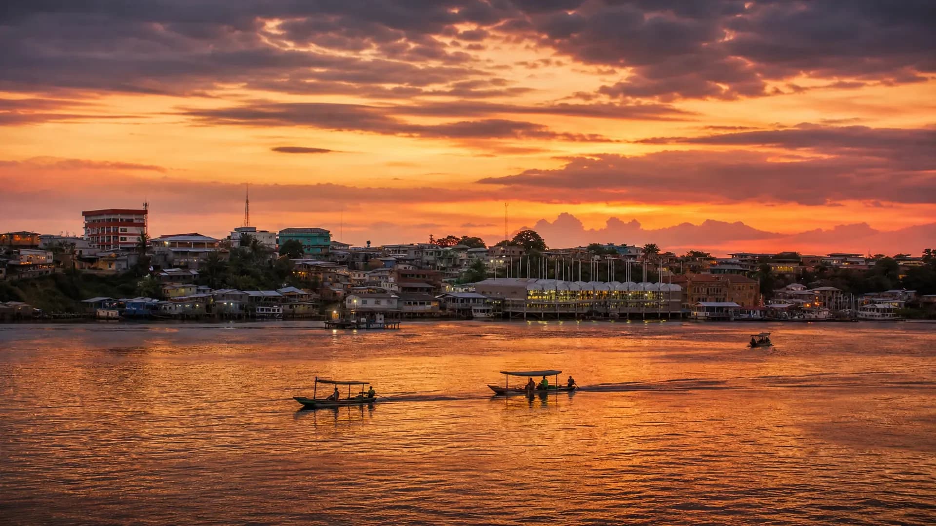 Vista aérea de Tefé ao amanhecer, com a cidade na margem direita e o lago de Tefé se abrindo à esquerda